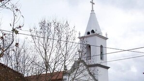 A church with a bell tower, a wooden door, and a stone wall.