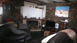 A cozy living room with a fireplace, leather sofas, and a stone wall.