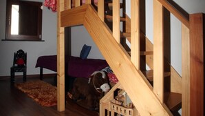 A wooden staircase with a built-in toy train track leading to a bed.