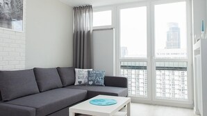 Una sala de estar moderna con un sofá gris, una mesa de centro blanca y una alfombra gris.