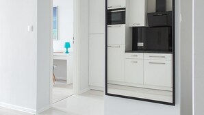 Una cocina moderna con armarios blancos, una campana extractora negra y un espejo grande en la pared.
