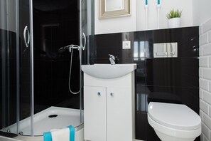 Un baño moderno con cabina de ducha de vidrio, lavabo blanco y retrete.