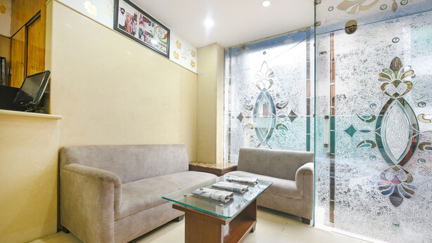 Un salon comprenant une table basse avec un plateau en verre, deux canapés et une porte décorative en verre ornée de motifs floraux.