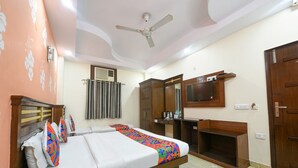 Une chambre d’hôtel équipée d’un lit, d’une armoire, d’un bureau, d’un miroir et d’un ventilateur de plafond.