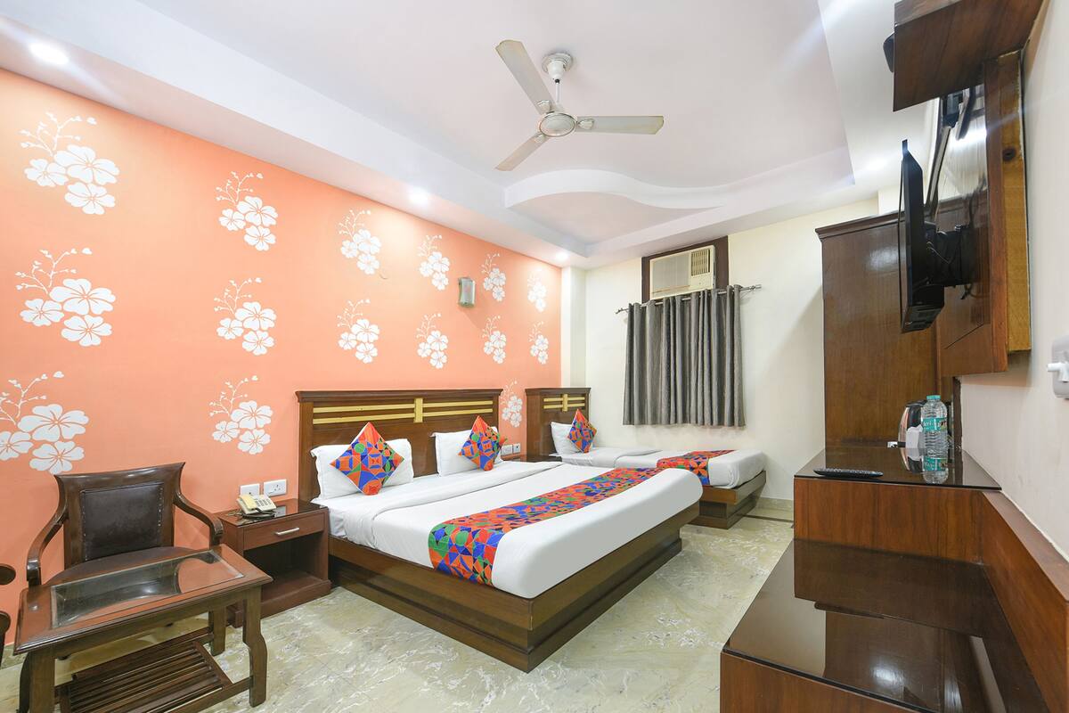 A hotel room with a bed, a chair, a desk, a TV, and a ceiling fan.