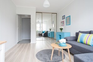 A modern living room with a grey sofa, a round wooden coffee table, and a blue cabinet. - Turquoise Studio Zelazna (Warsaw)