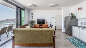 A modern living room with a sofa, TV, dining table, and chairs. - Morocco Mini Penthouse W Panoramic Views (Tiberias)