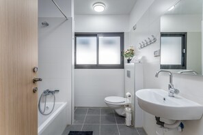 A modern bathroom with a toilet, sink, and bathtub.