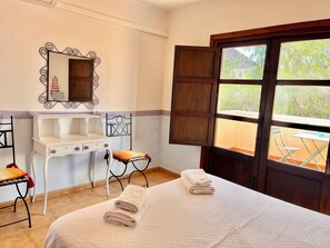 A bedroom with a bed, a desk, a chair, a mirror, and a window.