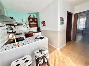 Une cuisine avec un dosseret carrelé, des meubles en bois et un petit îlot central avec des tabourets.
