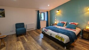 Un dormitorio con cama, una silla, una mesita de noche y una ventana con cortinas.