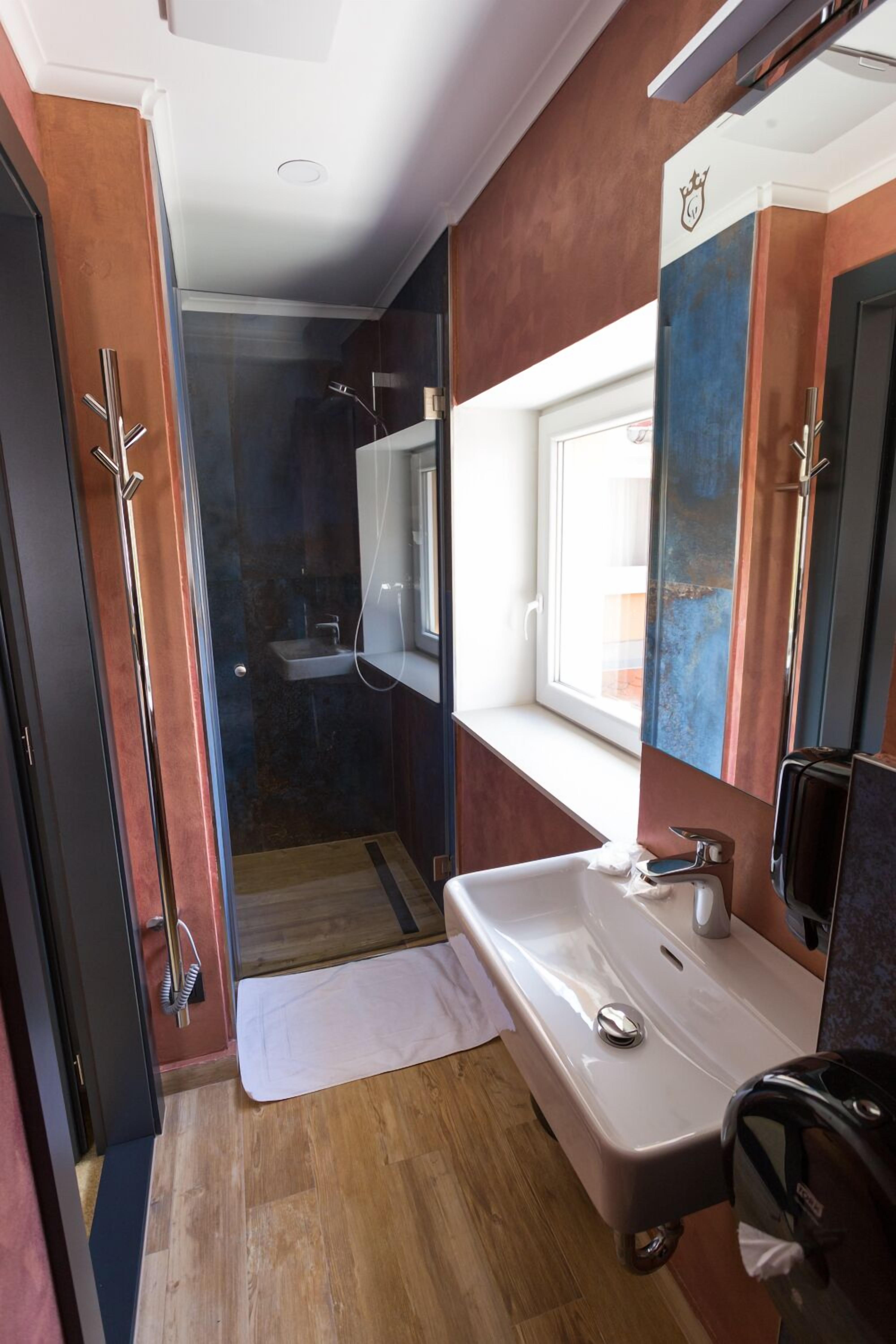 Een moderne badkamer met een douchecabine van glas, een witte wastafel en een grote spiegel.