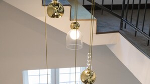 A staircase with a metal railing, a hanging light fixture, and a window with a view of the outside. - Golden Apartments (Kosice)
