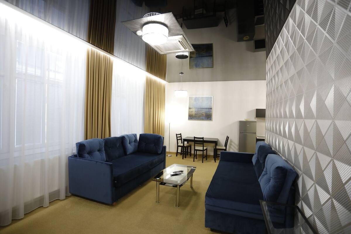 A modern living room with a sofa, a coffee table, and a dining area.