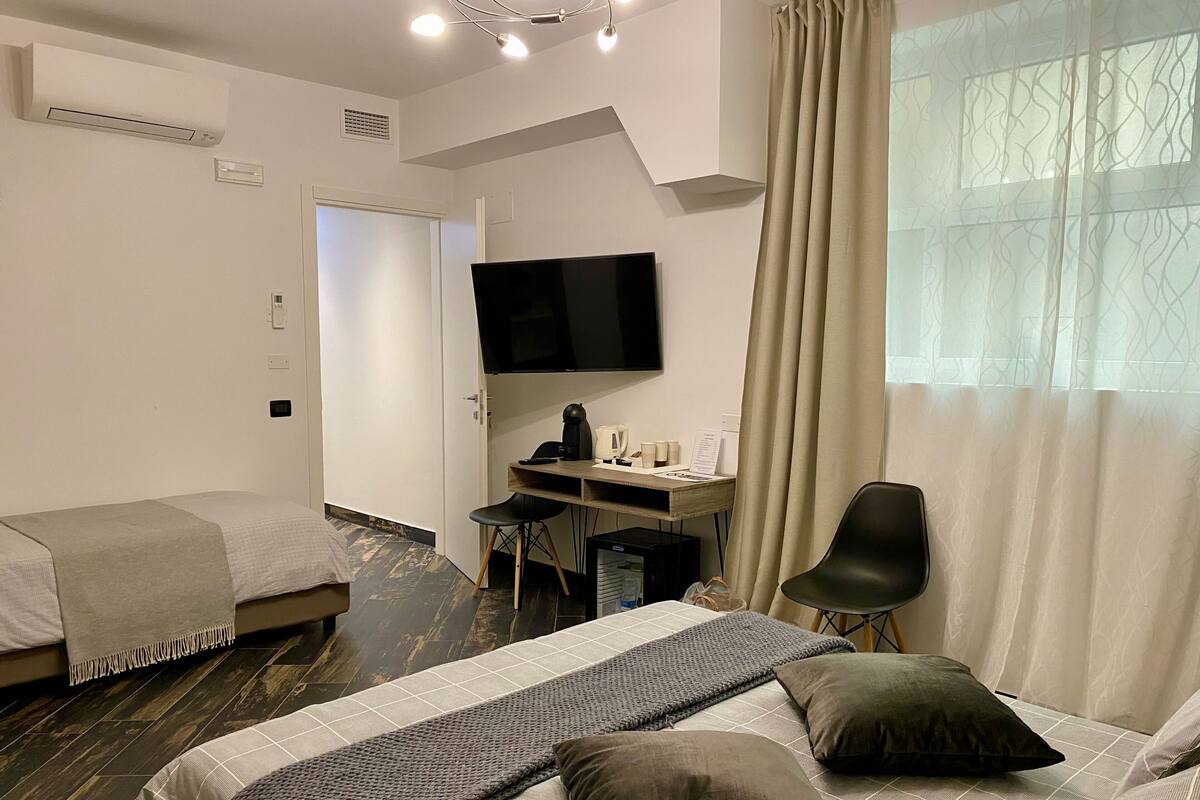 A hotel room with two beds, a desk with a computer, a TV, and a chair.