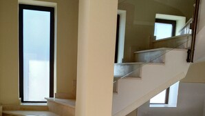 Una escalera conduce a un segundo piso con lavadora y armarios de madera.