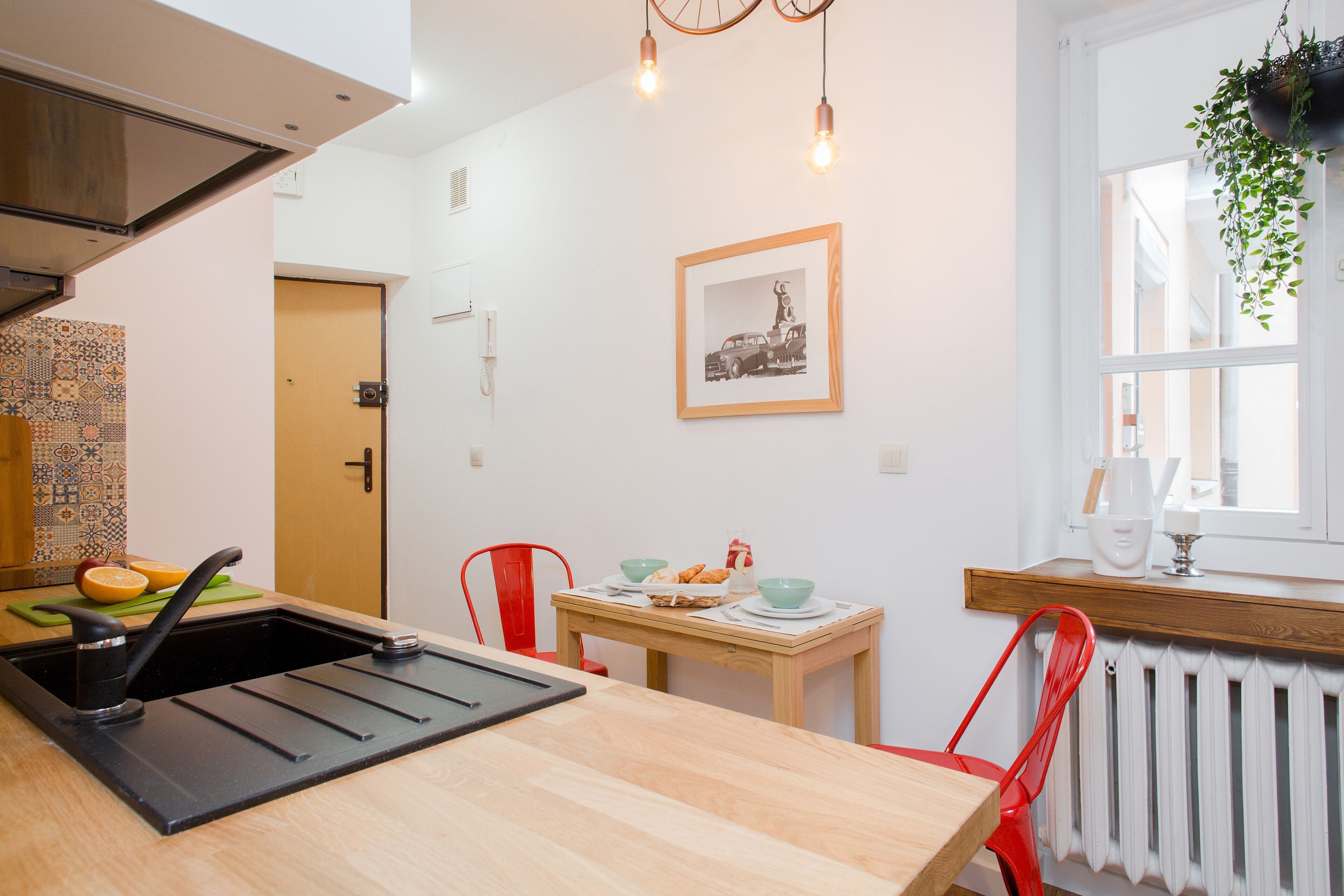A modern kitchen with a sink, a wooden table, and red chairs.