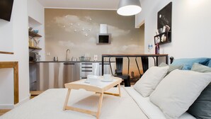 Ein modernes Schlafzimmer mit Bett, Nachttisch und Blick zur Küche.