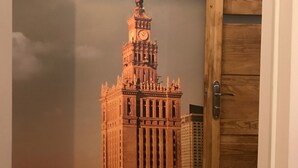 Ein Modell eines hohen, verzierten Gebäudes mit einem Uhrturm vor einer bewölkten Kulisse.