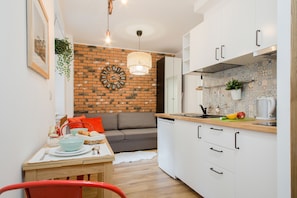 Uma cozinha moderna com armários brancos, parede de destaque em tijolo e área de jantar com mesa e cadeiras.
