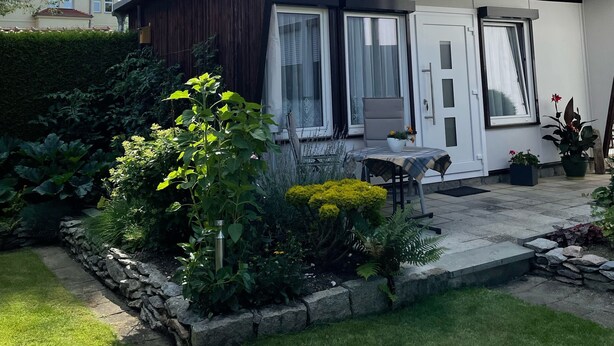 A modern house with a patio, stone pathway, and a variety of plants. - Holiday house in a quiet location and near the forest (Wernigerode)