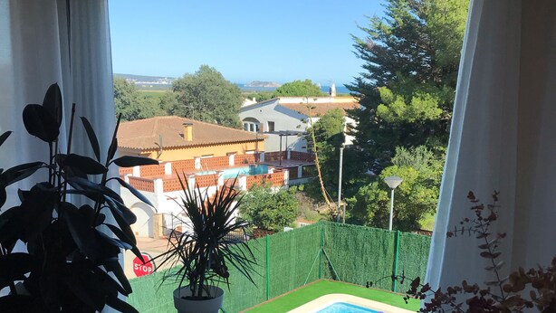 Ein Balkon mit Blick auf einen Pool, einem Esstisch und Topfpflanzen.