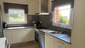 Eine moderne Küche mit weißen Schränken, einer Spüle aus Edelstahl und einem Fenster mit Blick auf Grünflächen.