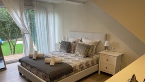 Ein Schlafzimmer mit Bett, Nachttischen, Vorhängen und Blick ins Freie.