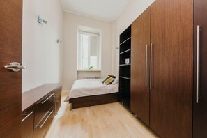 A bedroom with a bed, wooden wardrobe, and a window.