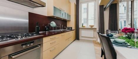 Une cuisine moderne équipée d’un four encastré, d’une cuisinière à gaz et d’un coin repas avec une table dressée pour deux personnes.