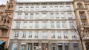 A multi-story building with a symmetrical facade, featuring a central entrance with a large door and several windows on each floor. - Apartment Cohen - Aleje Ujazdowskie (Warsaw)
