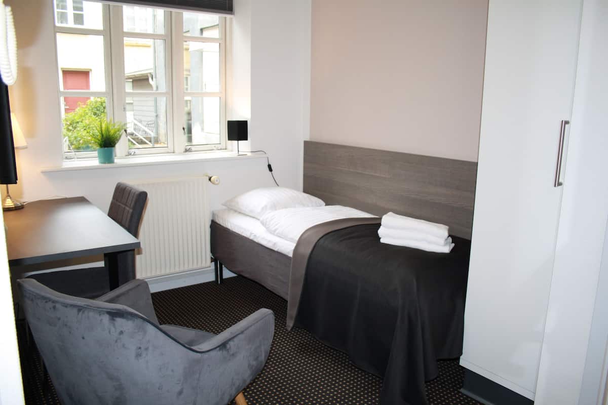 Een hotelkamer met een bed, een bureau, een stoel, een raam met uitzicht en een radiator.