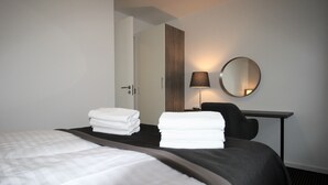 Une chambre d’hôtel avec un lit bien fait, un bureau avec une chaise, une lampe et un miroir.