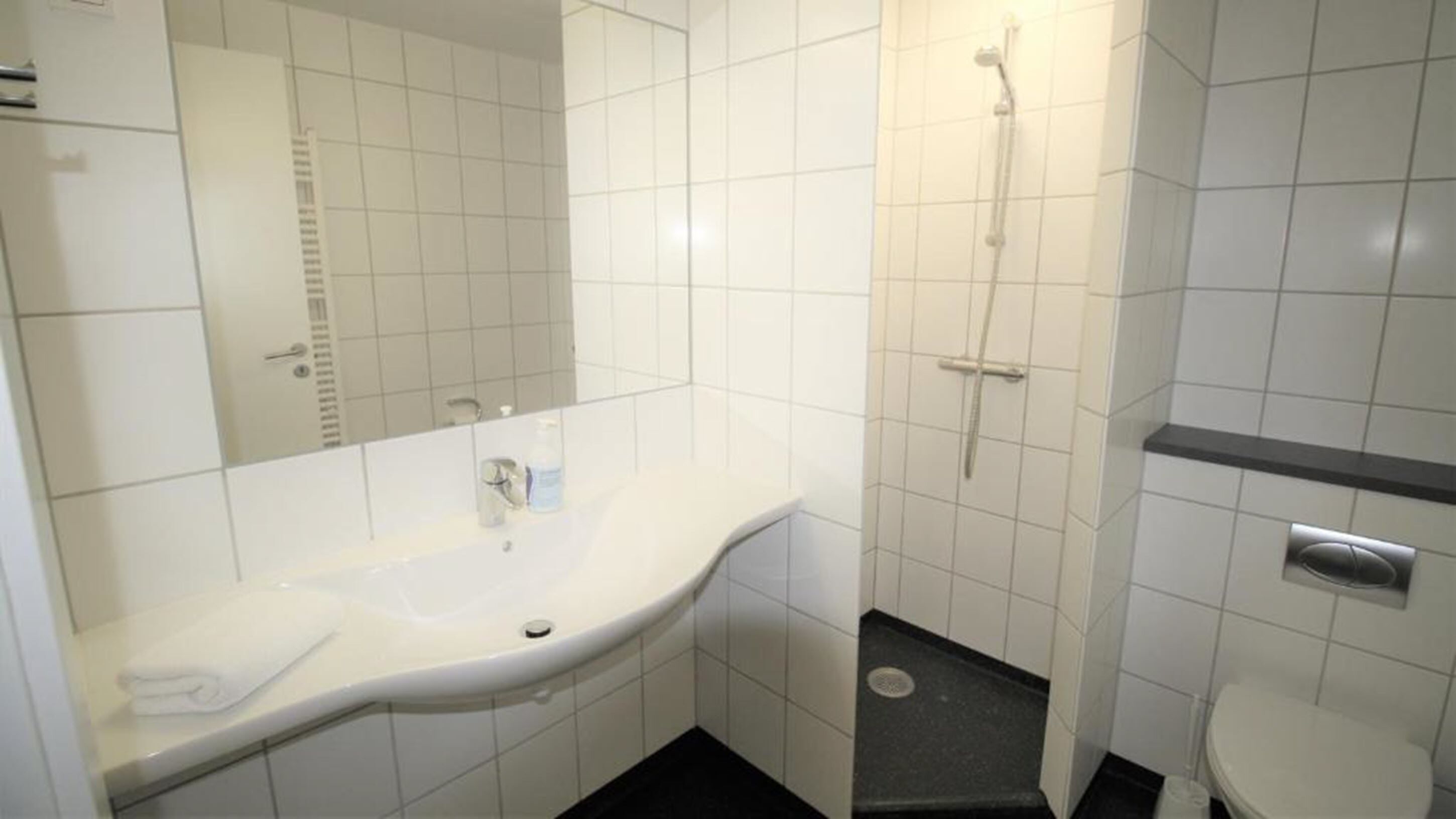 Ein Badezimmer mit Waschbecken, Spiegel und Dusche.