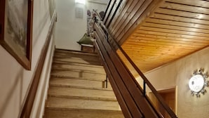 A wooden staircase with a handrail, leading to a landing with a light fixture. - Rosy's House Pension Privatzimmer (Bad Goisern)