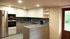 Una cocina moderna con electrodomésticos de acero inoxidable, encimera de mármol y armarios empotrados.
