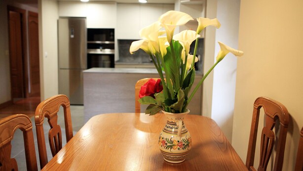 Une table à manger avec un vase de fleurs et des chaises.