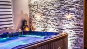 A spa area with a hot tub, a stone wall, and a wooden door. - Camping Site de Gorge Vent (Fréjus)