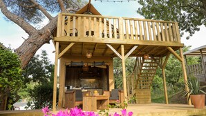 A wooden deck with a built-in grill and seating area, surrounded by trees and a garden. - Camping Site de Gorge Vent (Fréjus)