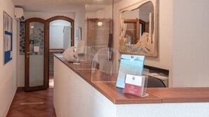 Un espace d’accueil avec un comptoir en bois, une vitrine et une œuvre d’art encadrée au mur.