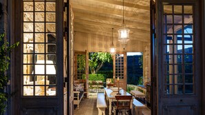 An open wooden door leading to a dining area with a bench, table, and hanging light fixture. -  A Grand Estate, with 2 Pools, Gym & Tennis Court (Peza)