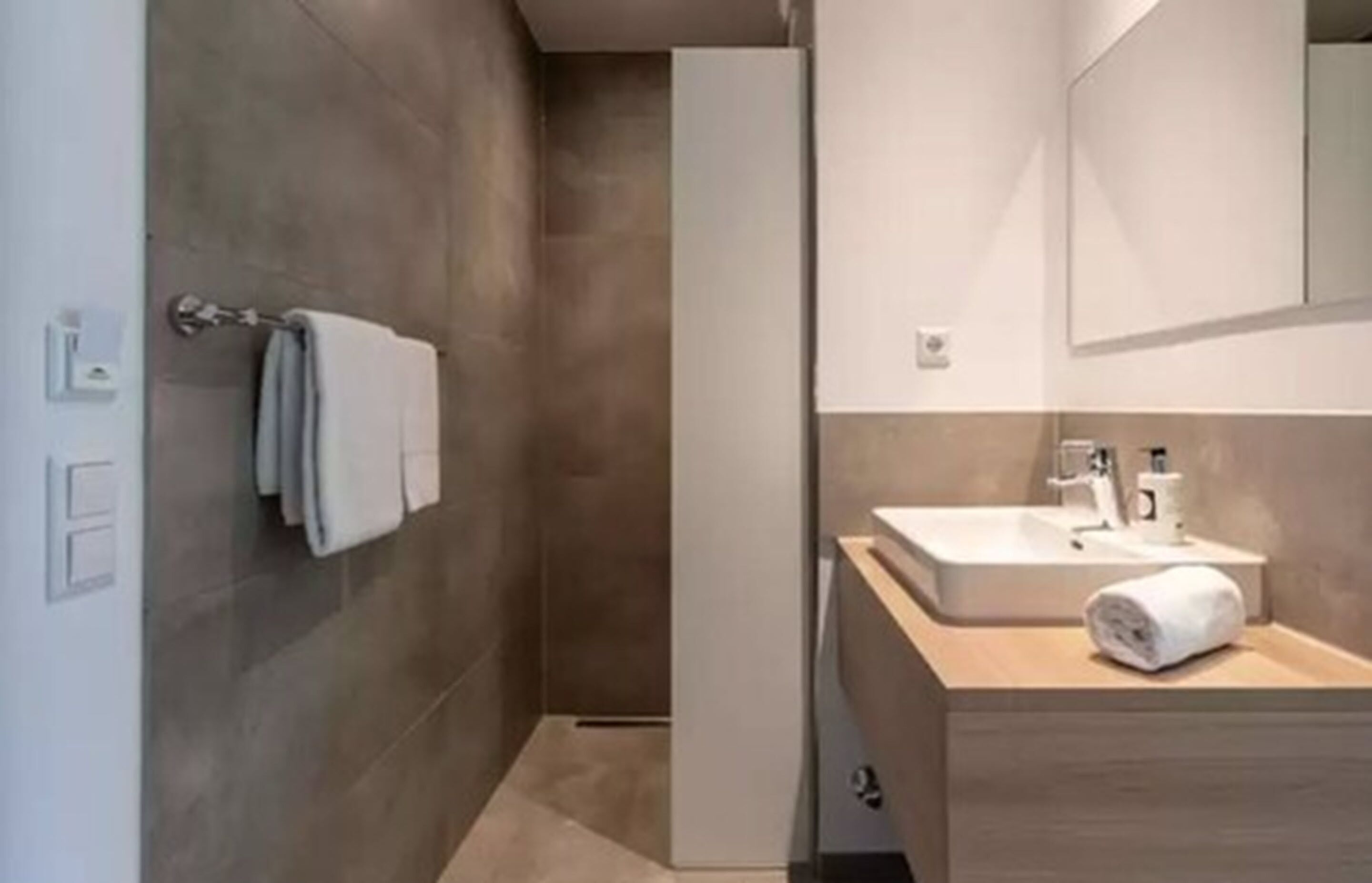Un baño moderno con ducha, lavamanos y espejo.