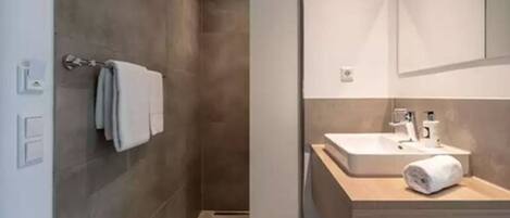 Un baño moderno con ducha, lavamanos y espejo.