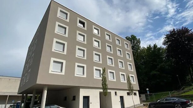 A modern building with a flat roof, multiple windows, and a parking area with cars. - a2 Hotels Wernau (Wernau)