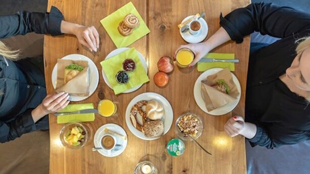 A wooden table with various breakfast items including pastries, fruits, and beverages. - a2 Hotels Wernau (Wernau)