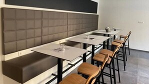 A modern dining area with high-backed booths and long tables, equipped with chairs and a few small tables. - a2 Hotels Wernau (Wernau)