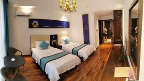 Une chambre d’hôtel avec deux lits, un bureau, une chaise, un lustre et un grand miroir.