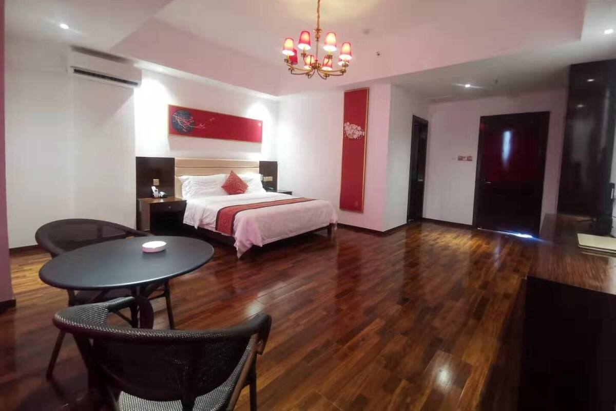 Habitación de hotel con cama, escritorio, silla, mesa redonda y candelabro.