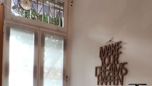 Ein Zimmer mit einer Schiebeglastür, die auf einen Balkon führt, einem Wandzeichen und einem weißen Schrank.