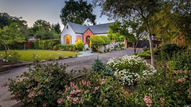 Een huis met een verzorgde tuin, een oprit en een klein voortuintje.